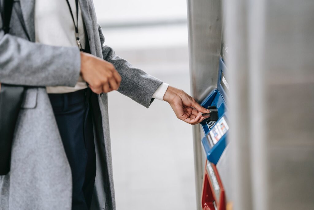 Hombre de chaqueta gris con pantalones retirando tarjeta de debito en un cajero automático